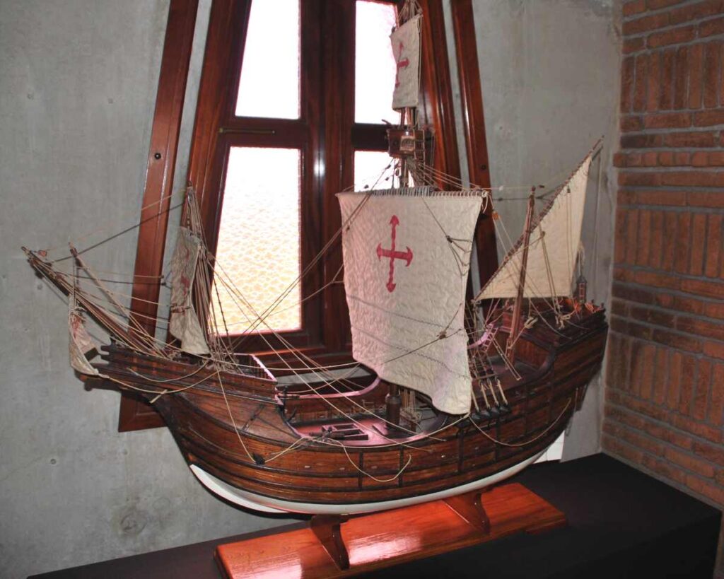 Maqueta de madera de una carabela con velas blancas y cruces rojas, expuesta en el museo del Faro a Colón
